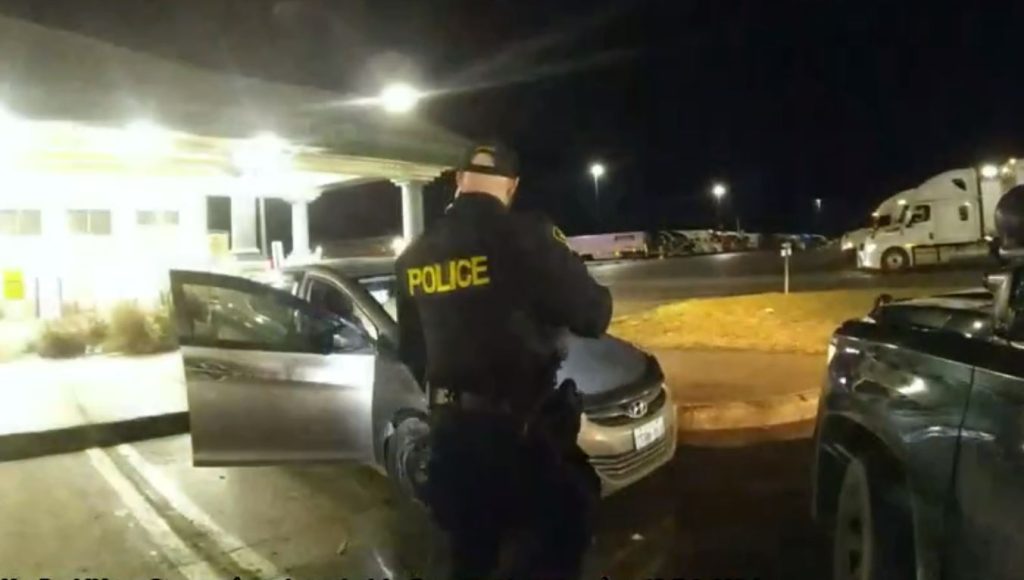 police officer approaching vehicle at night