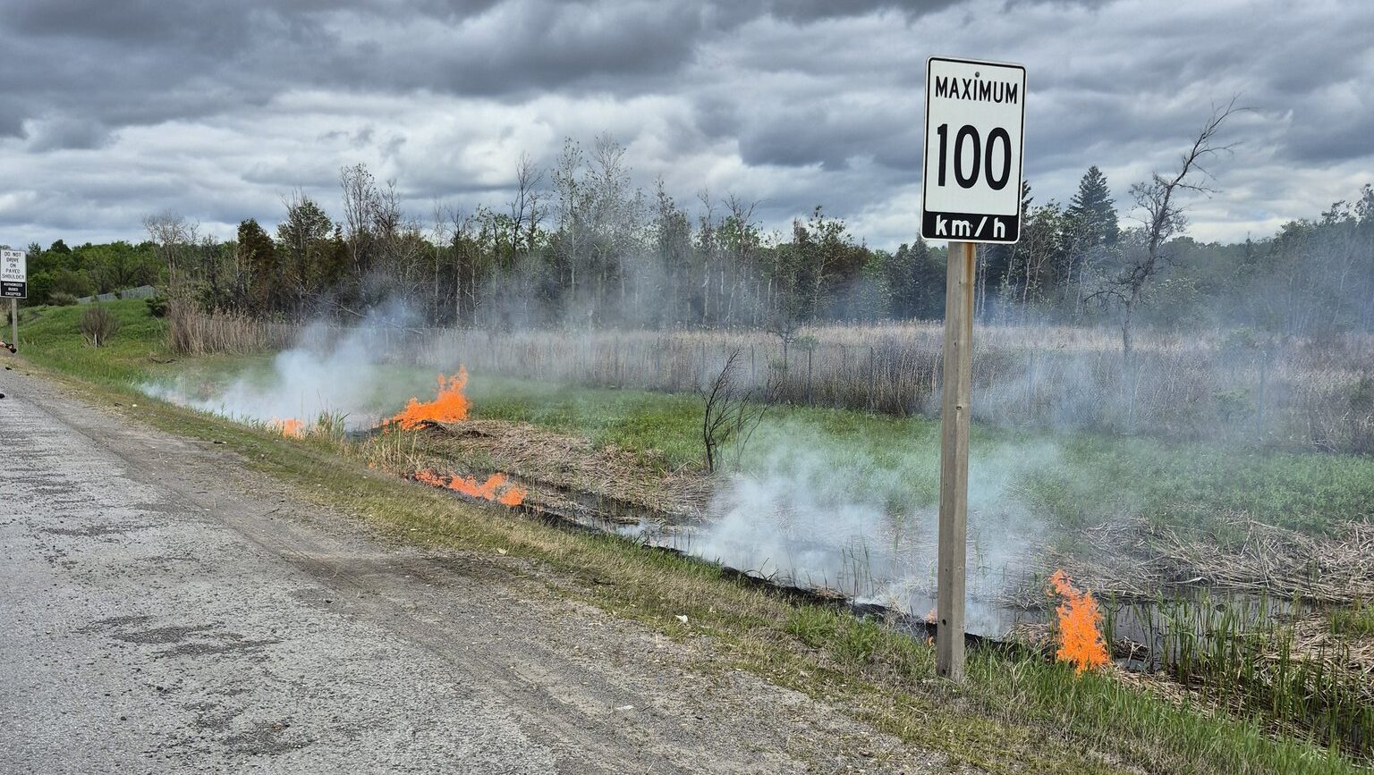 Flames burned through dry grass beside Hwy. 417 in the west end